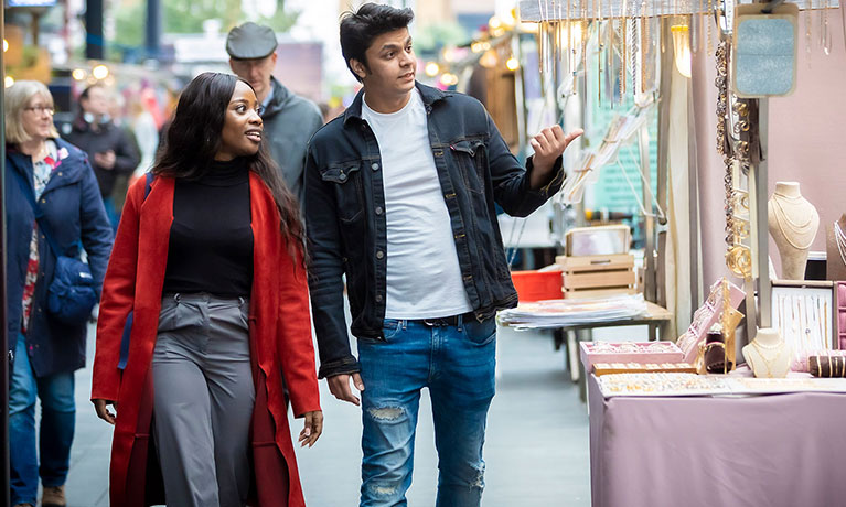 Two students walking through a market in London.