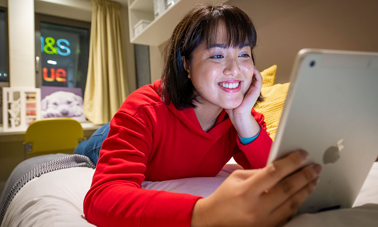 Student on bed looking at device