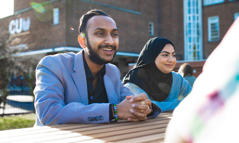 Student sitting on a table outside the campus building 