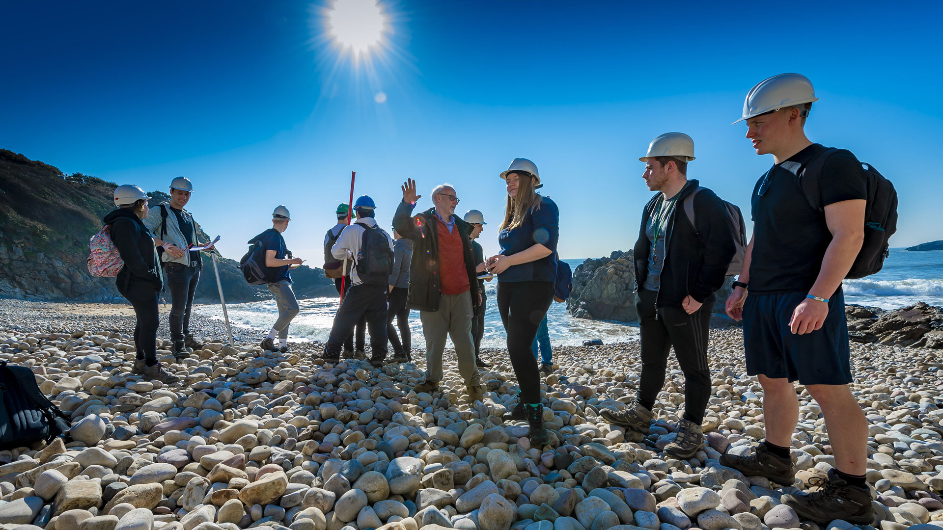 Geography students on a rocky beach with a lecturer