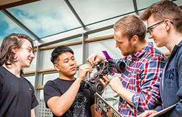 Four students engaged in a collaborative project working on a wired electric vehicle