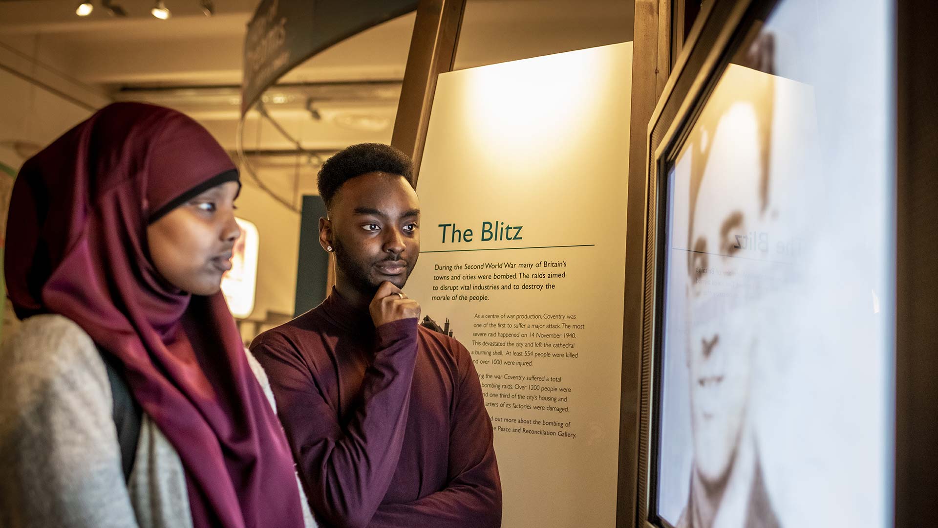 Two people reading on a screen where there is information about the blitz