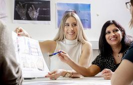 Students sitting around a table looking at a design drawing