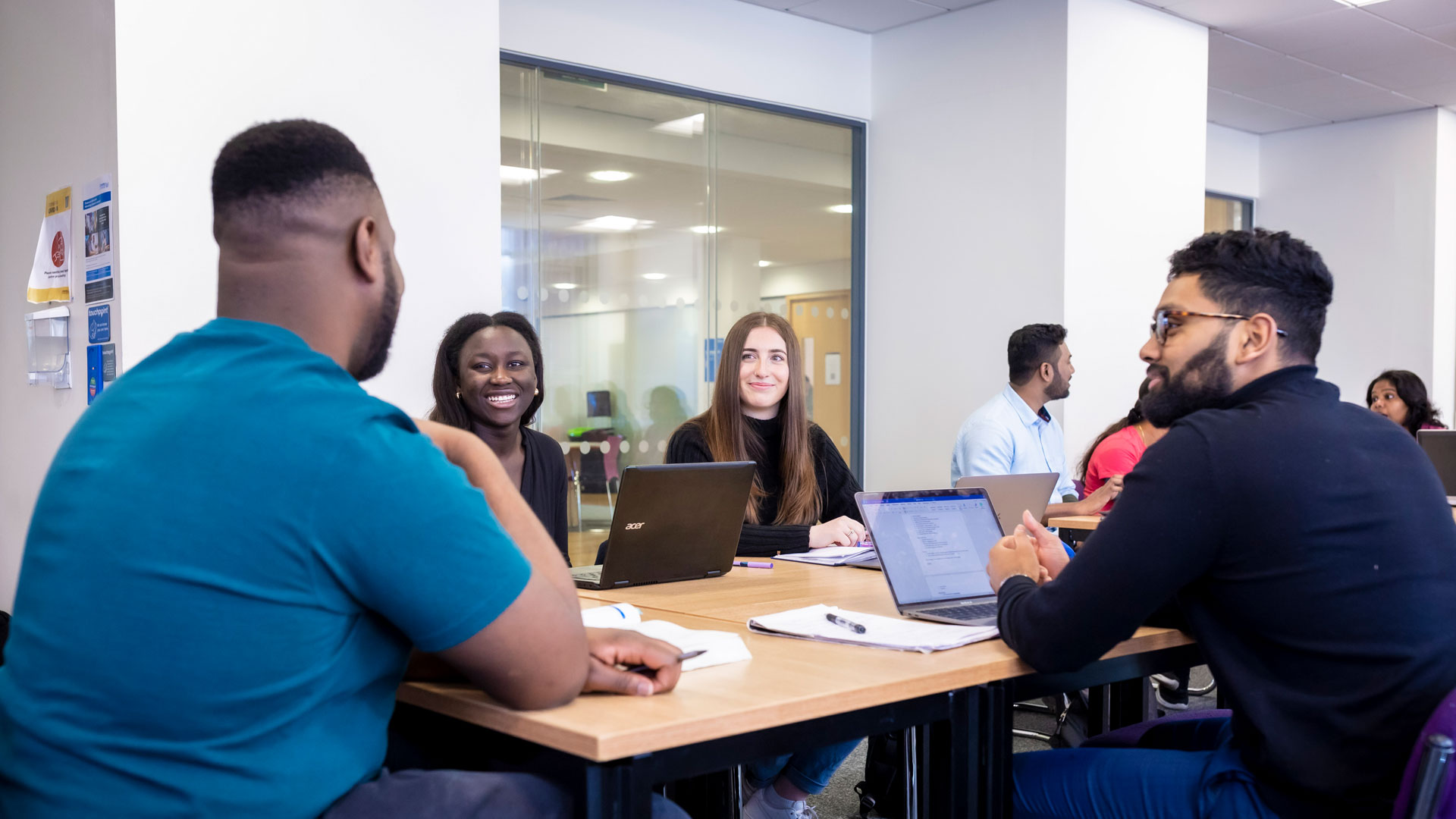 A group of students around a table smiling and talking. 