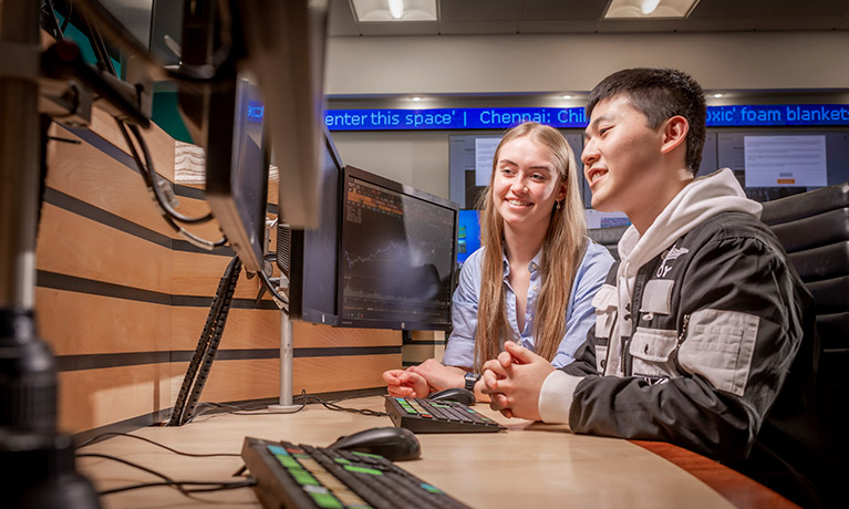 Two students sat working at a Bloomberg terminal