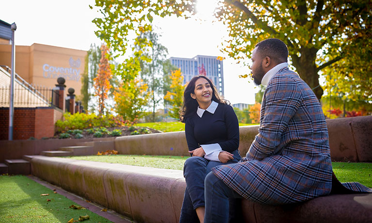 Two students sat outside the library talking 