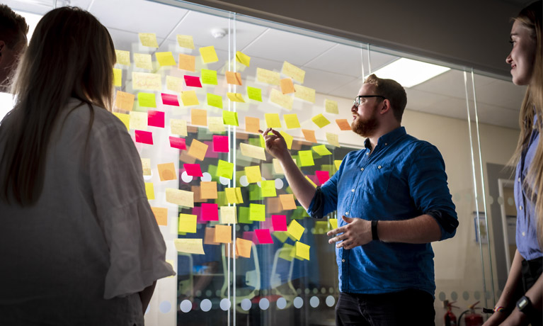 A lecturer and students using a think board