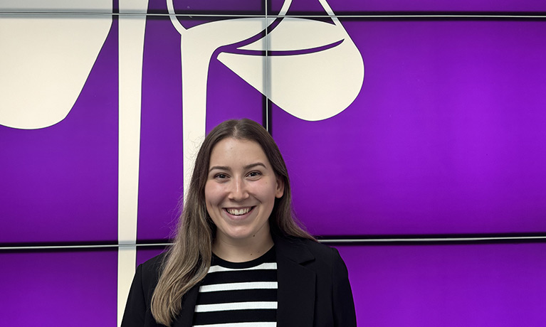 A portrait of Sabina at Cadbury's world in front of a Cadbury's illustration of a glass of milk