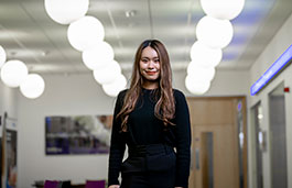 Student stood inside the william morris building smiling with circular lights in the background