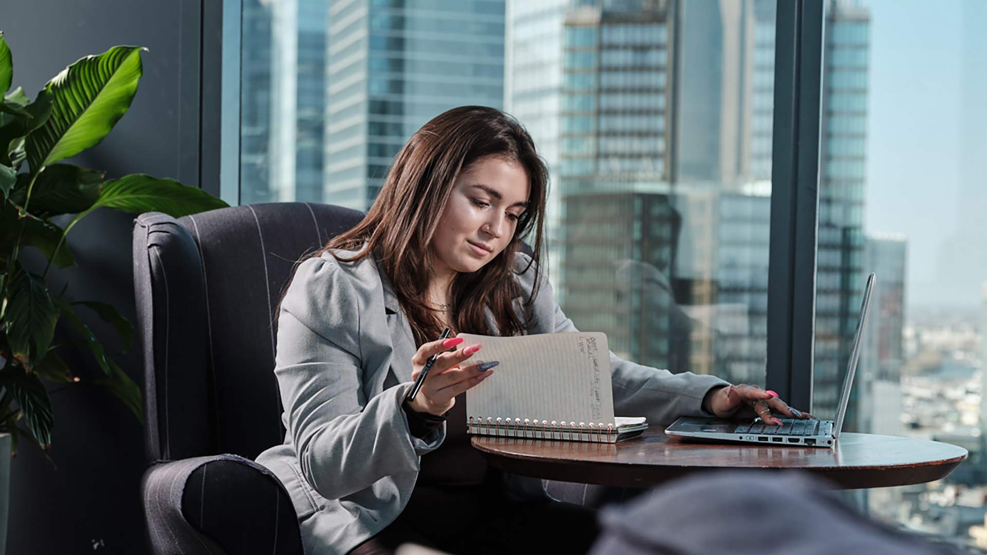 Female student in smart dress sitting at a desk looking at a notebook and laptop hair looking at a tablet