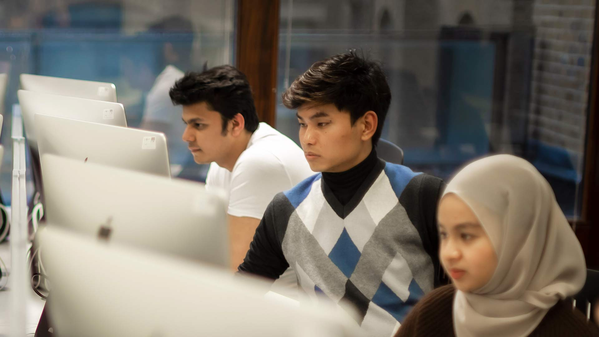 3 students working intently staring at monitors