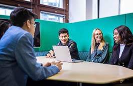 4 professionally dressed young students sitting in a study booth 