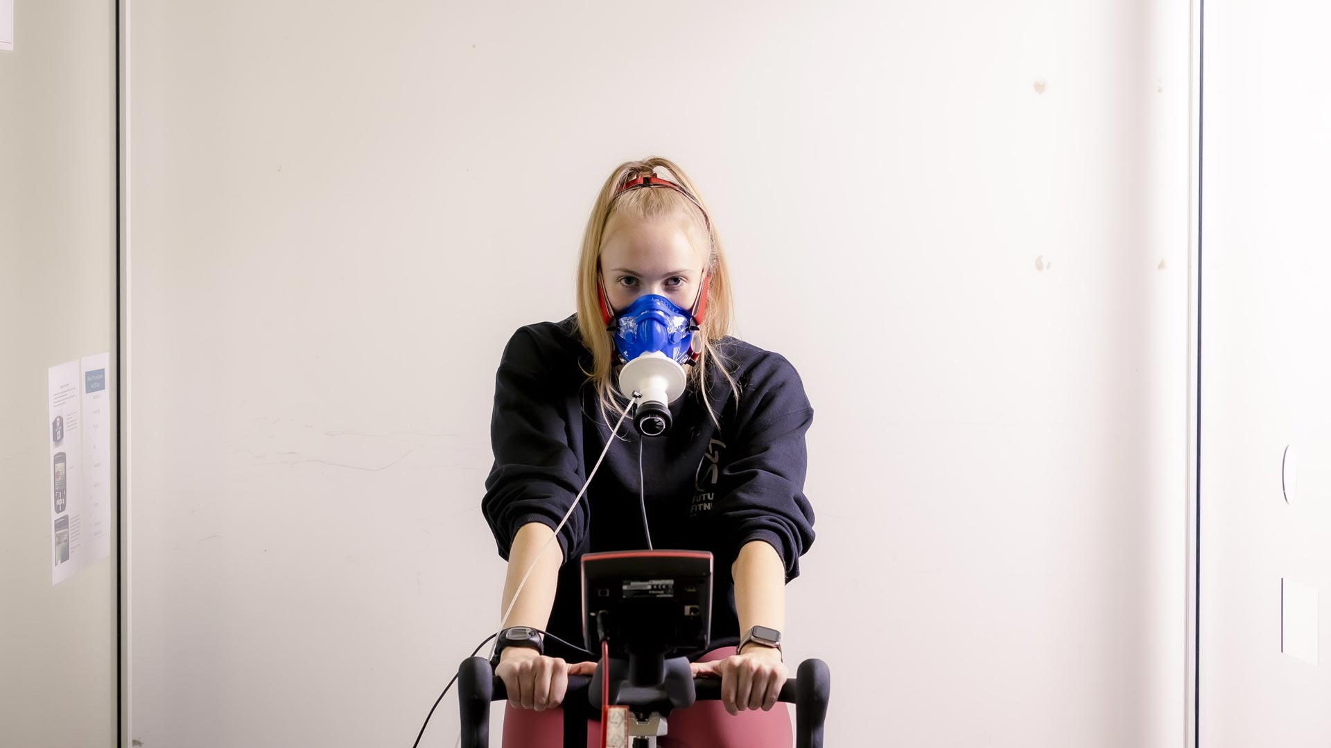 Student using exercise bike and breathing measurement equipment.