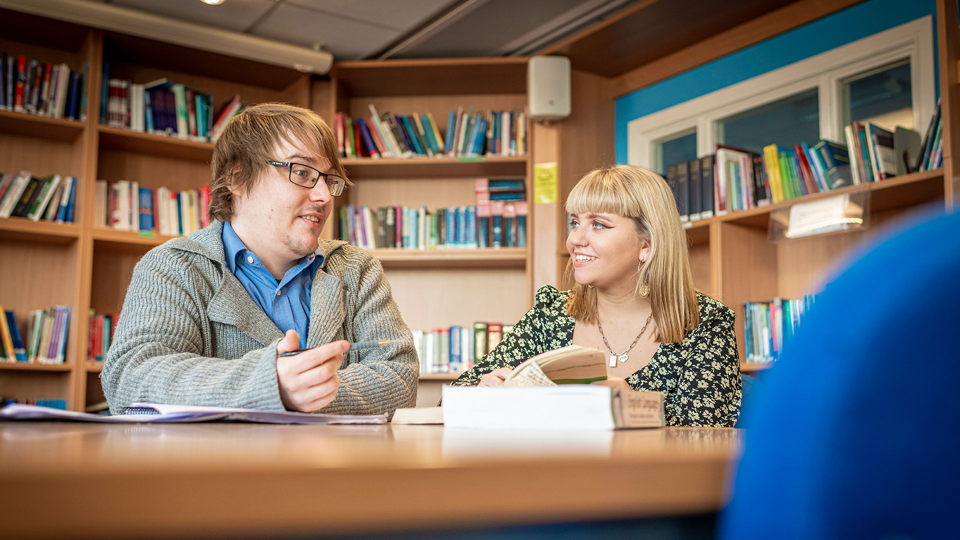 Two students sat in a library talking