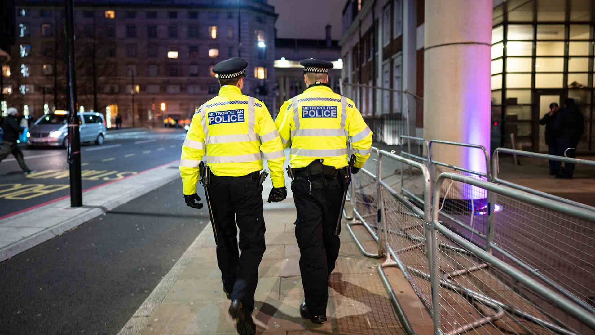 A couple of police officers walking down a city street in the night