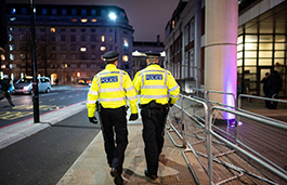 A couple of police officers walking down a city street in the night