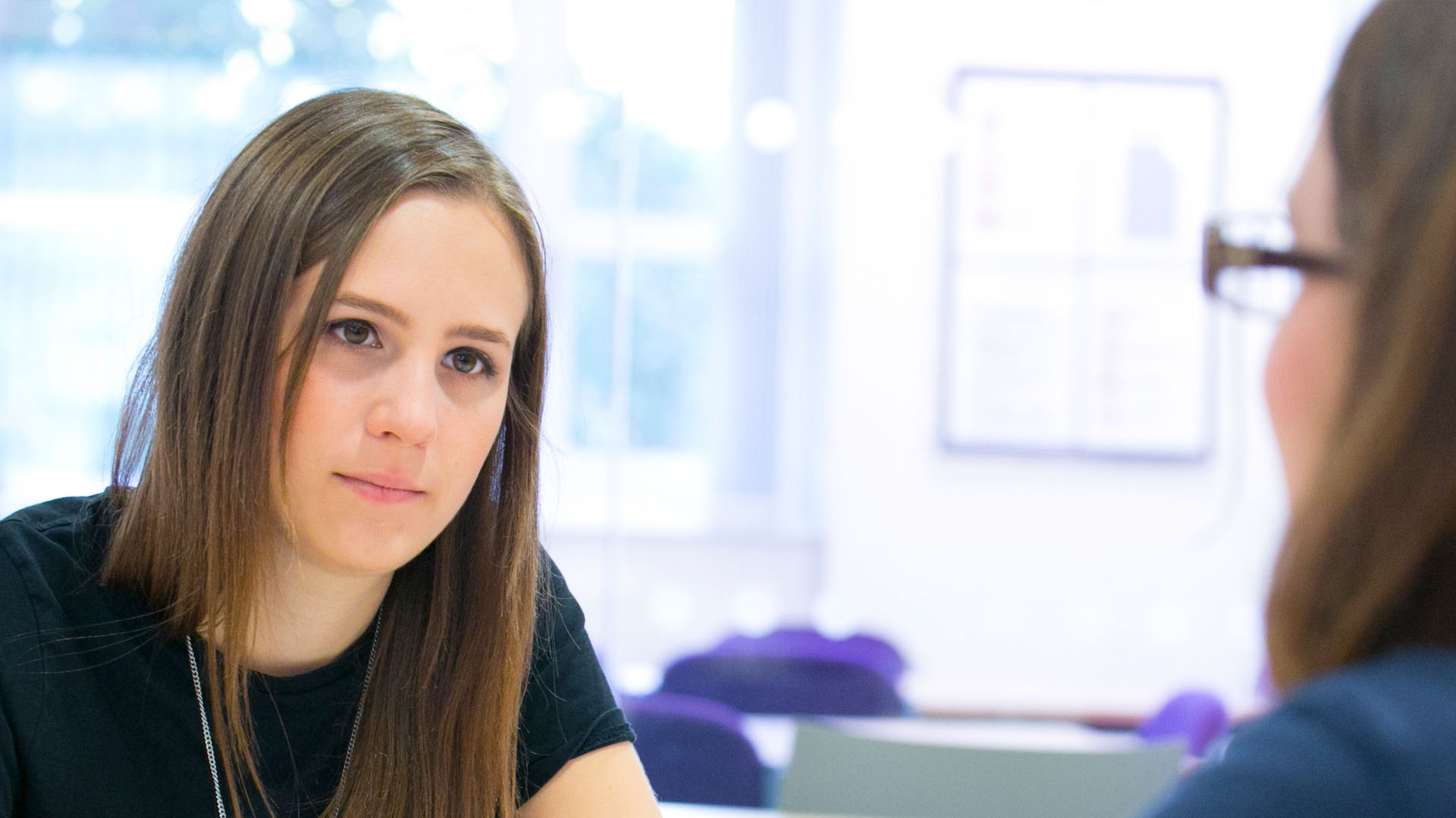 close up head shot of a young female student chatting to another female 