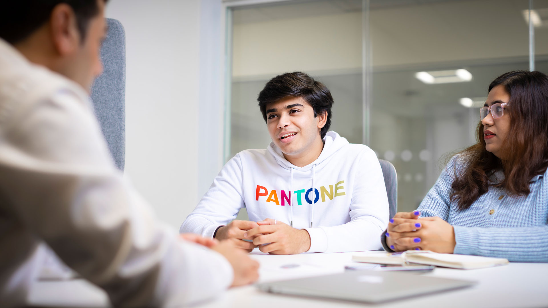 Two students discussing something with another person looking towards them