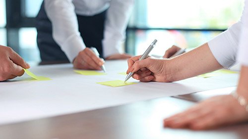 Designers working on a large piece of paper with highlighter pens 