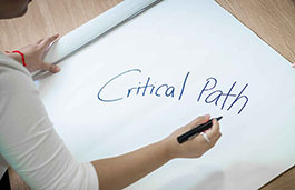 student writing critical path on white board 