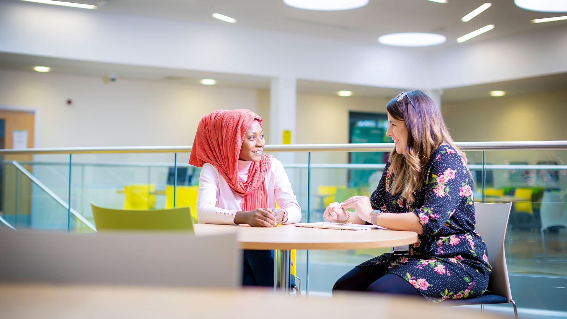 Two students sit on the seats and talk happily.