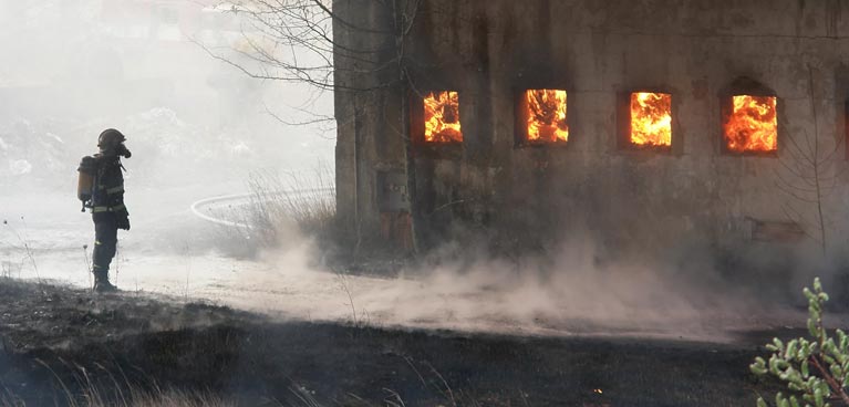 Fireman stood looking into building filled with fire