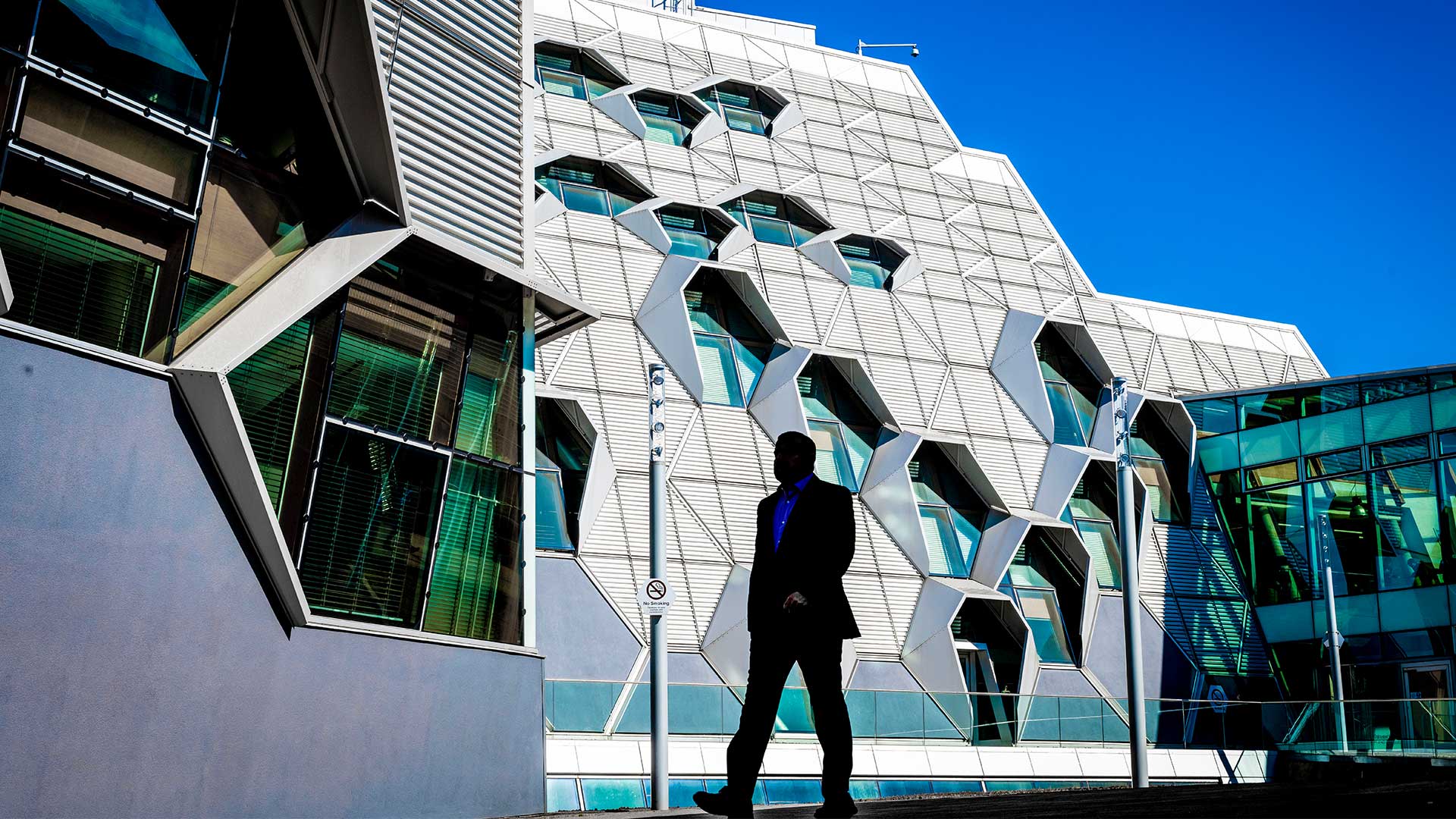 Student walking past the engineering buildng on a sunny day