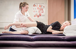 A physiotherapist working on a patient lying on the therapy couch receiving treatment