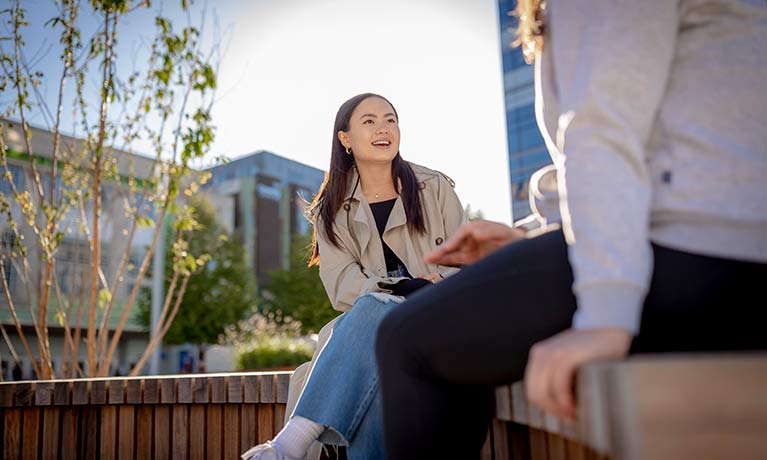 Girl smilng sitting outside on bench 