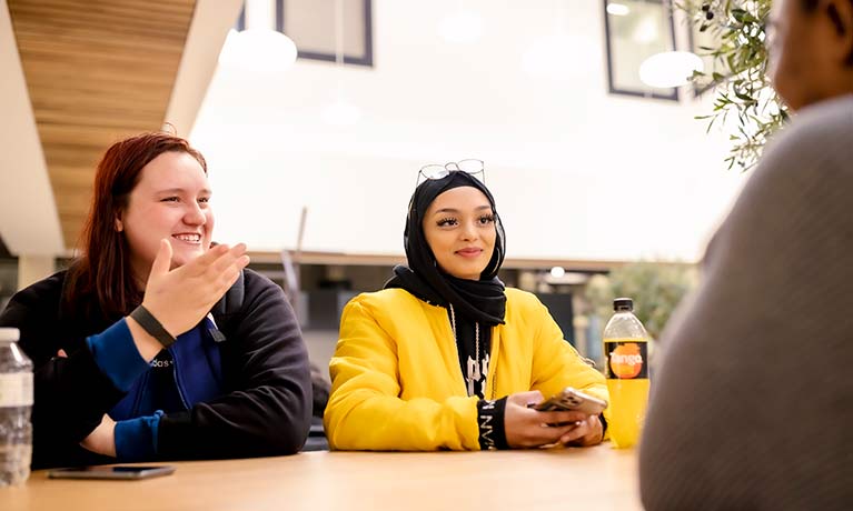 Two female students at a table chatting