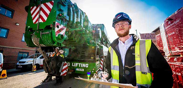 Engineer wearing a hard hat and hi vis with a clip board at a construction site