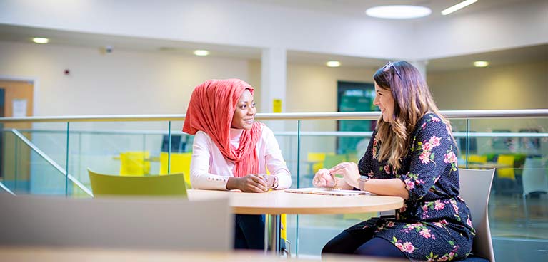 two students chatting across a table