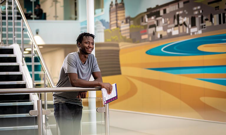 Student looking over the balcony of a campus building