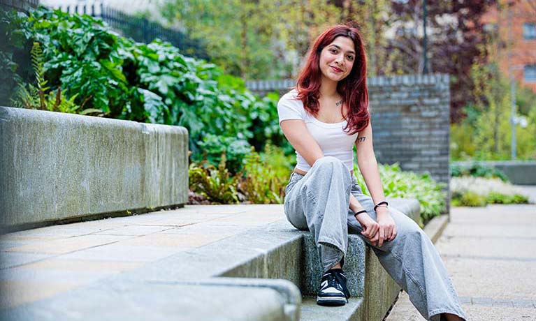 A young female smiling sitting on steps outside campus