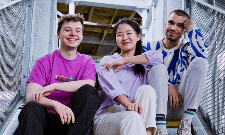 Three students sitting on an external stairwell