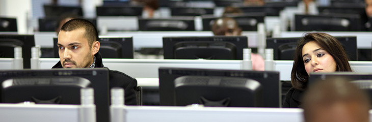 Students sitting at a bank of screens