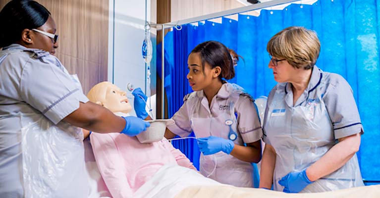 Student nurses practicing on a training manikin