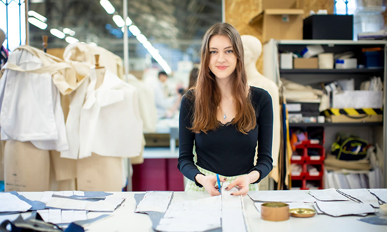 Female student stood in a workshop cutting material