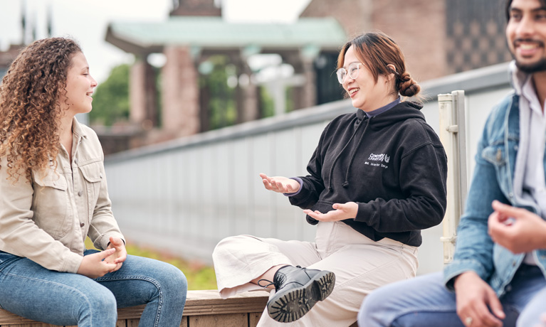 Students sitting chatting on top of The Hub campus building