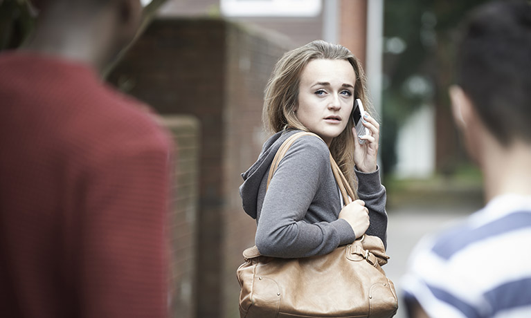 Woman on her phone looking back to two men standing behind her