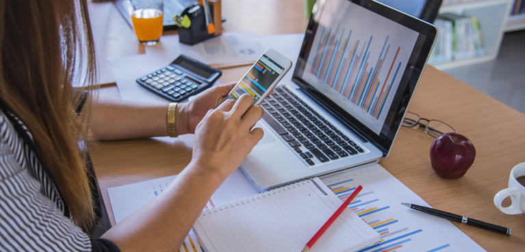 Woman looking at her phone working at a desk