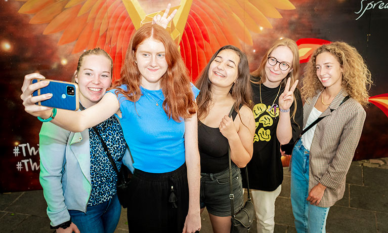 Group of students taking a photo in front of wall art