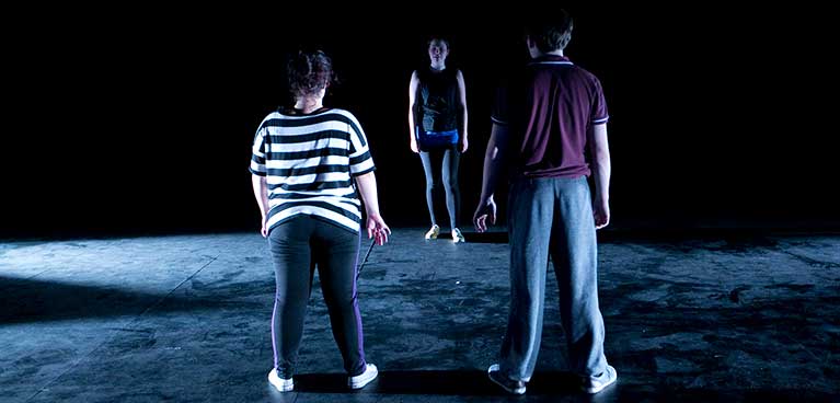 Students standing in a dramatic dark area