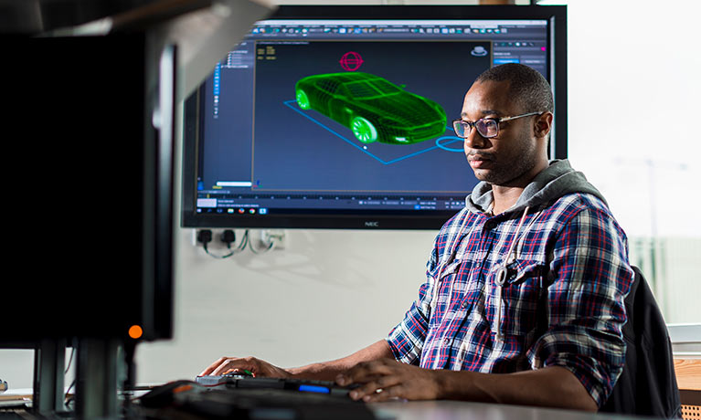 BAME male student working on multiple computer monitors