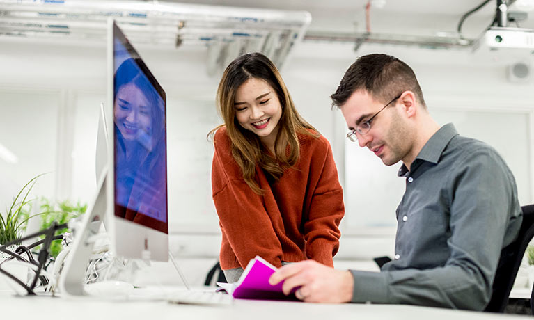 Two students working on a mac together.