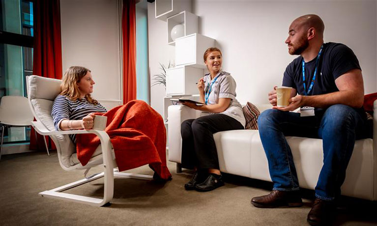 Patient, student and staff member talking in community house setting