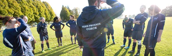 sports coach talking to students on a field