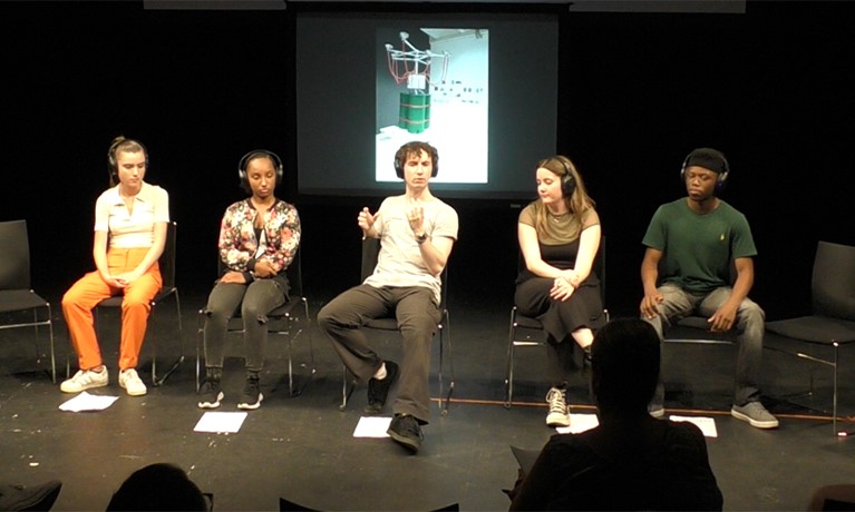 five people sat down talking on a stage