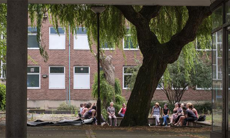 People sat down by a tree in front of a house