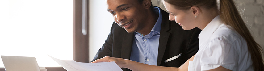 A male and a female wearing business attire reviewing a document